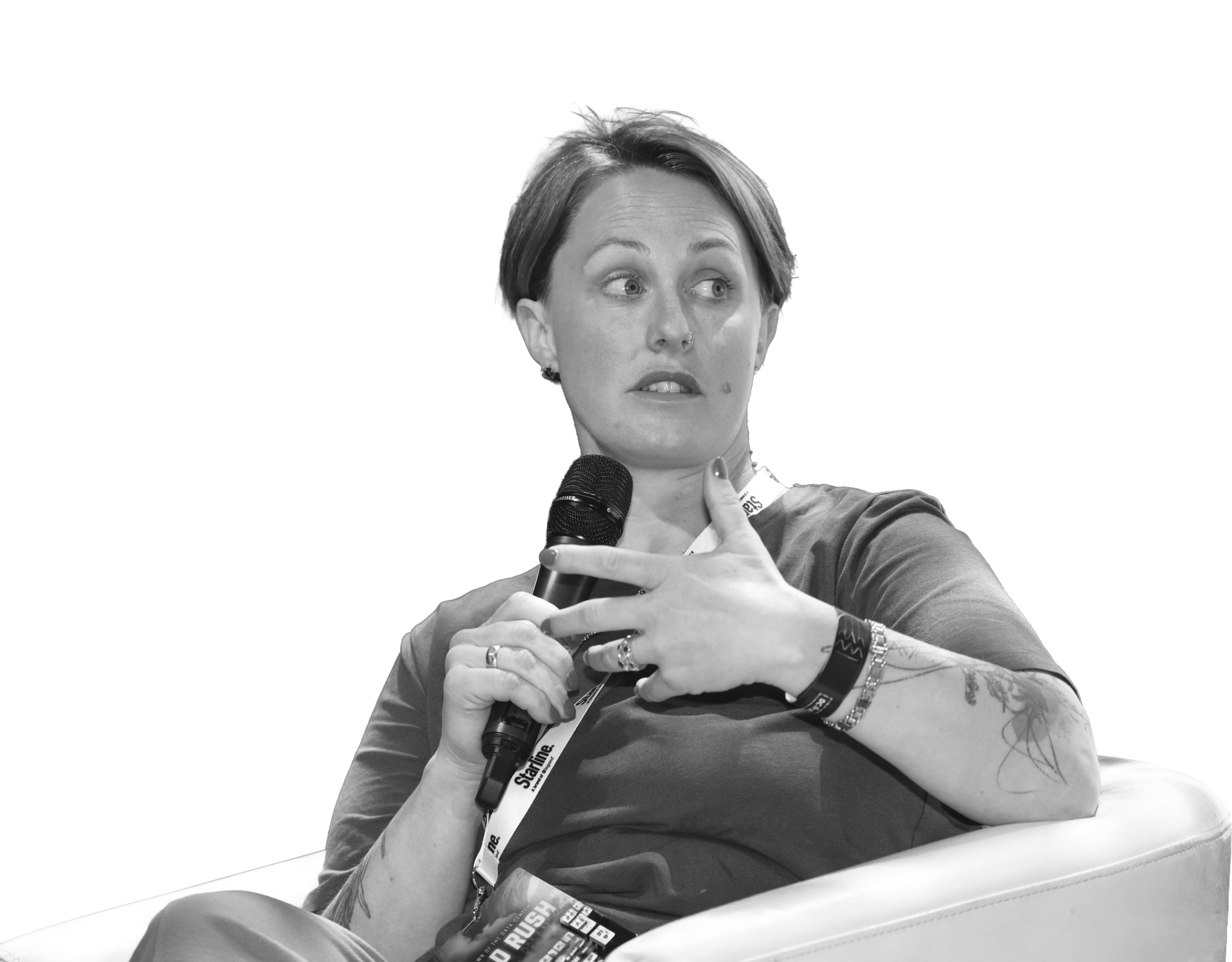 A woman speaks confidently while sitting in a chair on a conference stage